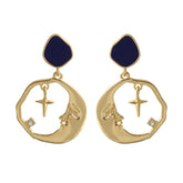 Elegant gold-plated earrings with crescent moon and cross design, adorned with a vibrant stone.